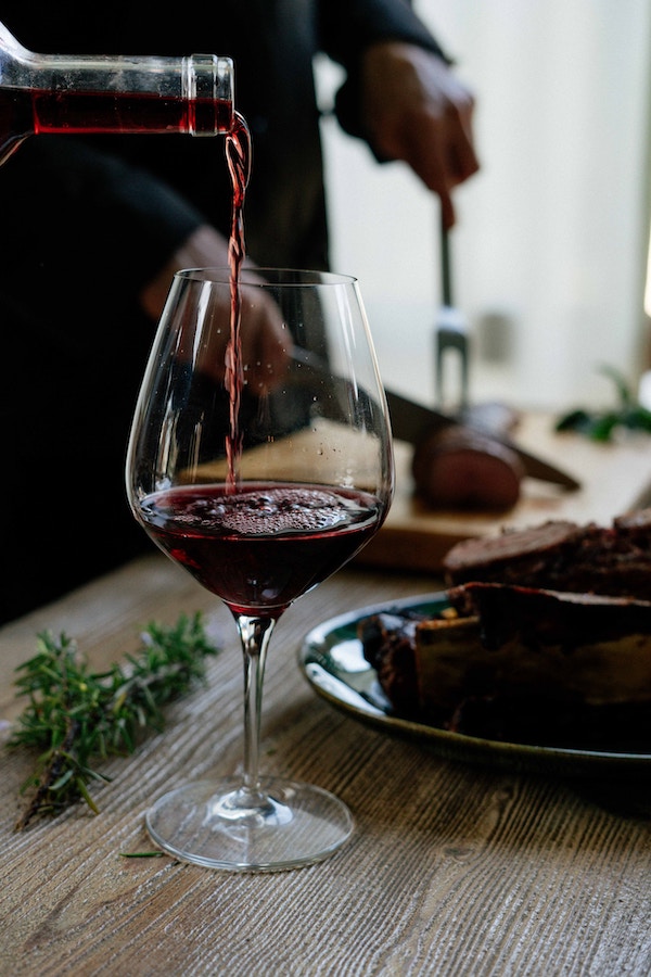 red wine being poured down into a wine glass
