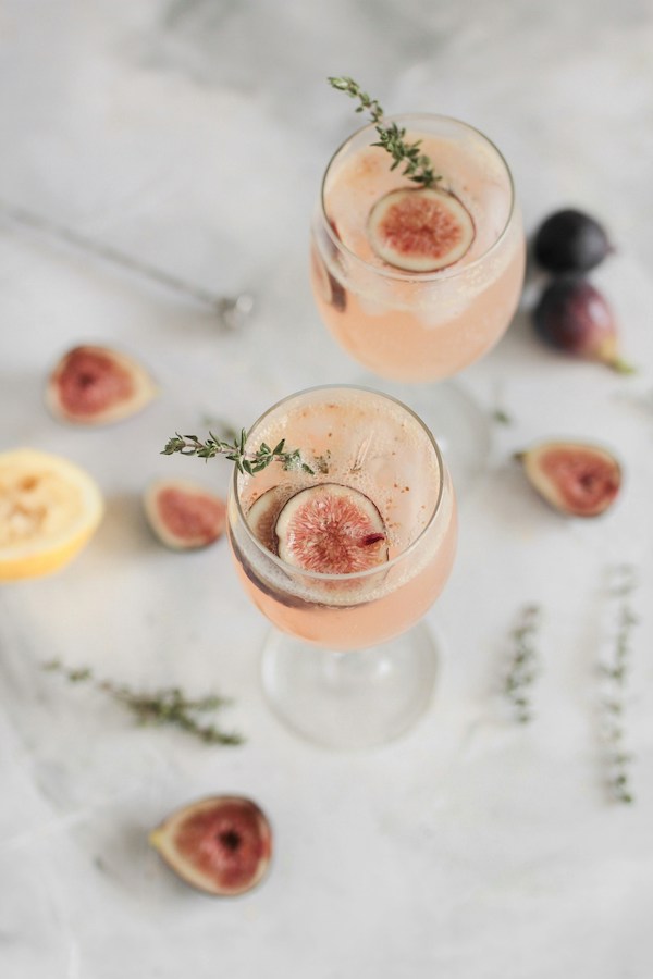 two pink cocktails with fig slices on top
