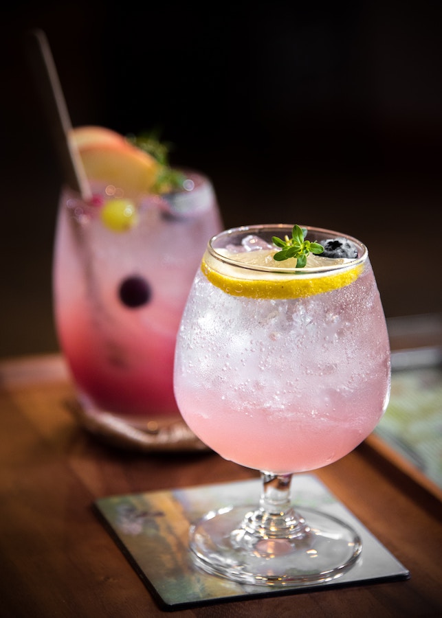 a pink cocktail with lemon and ice