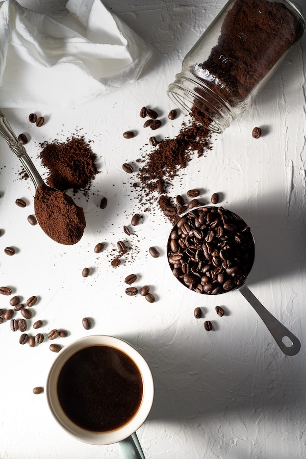 coffee beans and ground cofee on a white surface