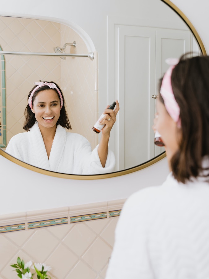 a smiling woman looking at herself in the mirror