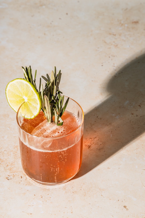 an orange cocktail with lime and rosemary