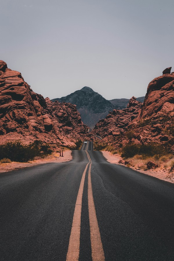 an empty road in a desert-like, rocky landscape, illustrating slow travel